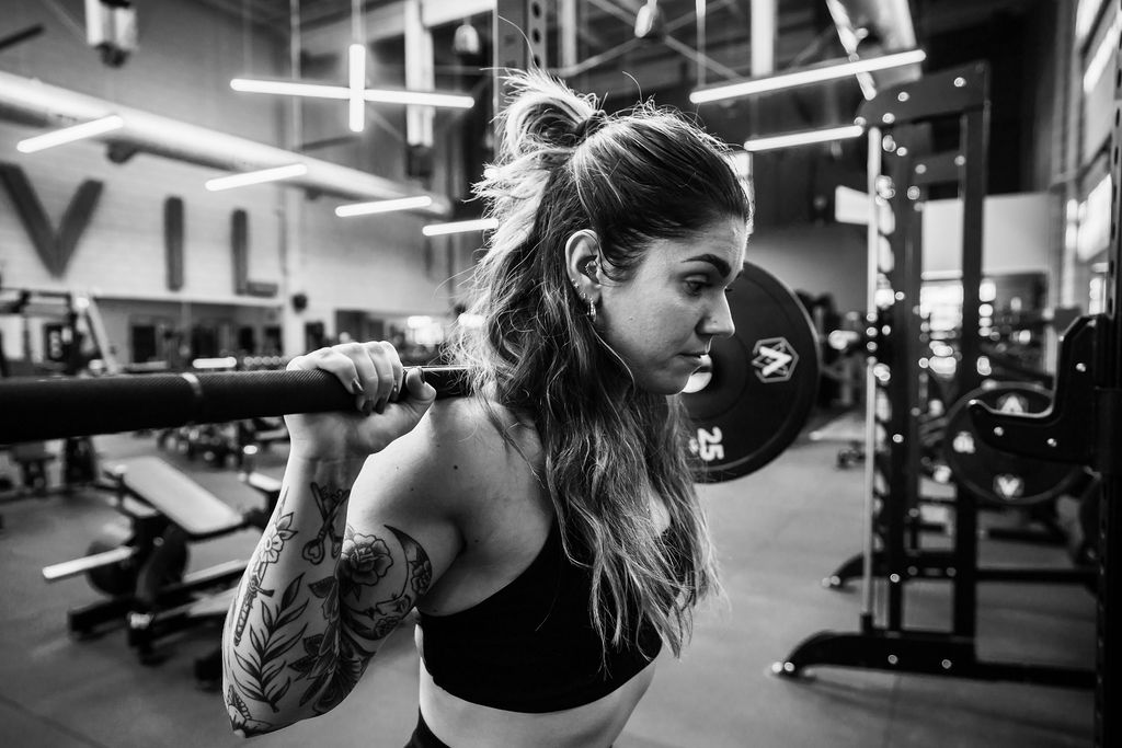 A member setting a barbell across her shoulders before a squat